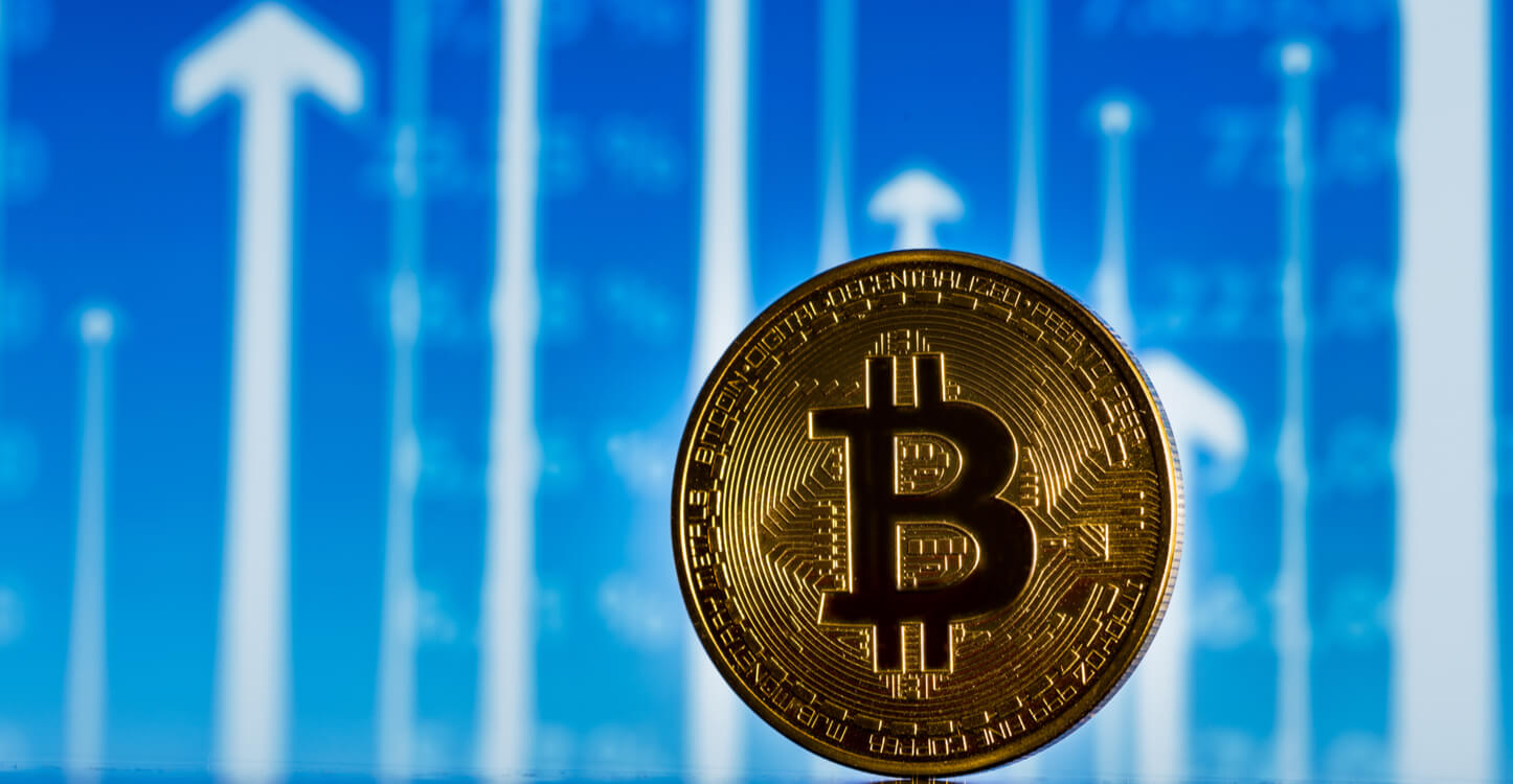 An image of a Bitcoin in front a background with arrows pointing up